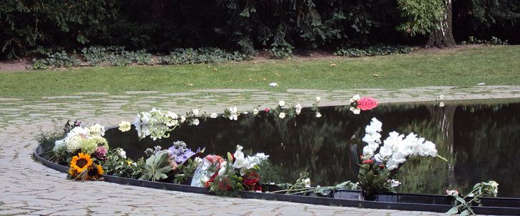 Blumen am Rand des Beckens vom Denkmal für die ermordeten Sinti und Roma Europas