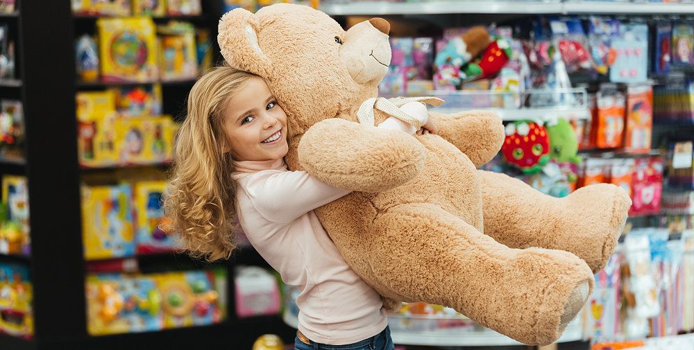 Mädchen mit großem Teddy im Spielzeugladen